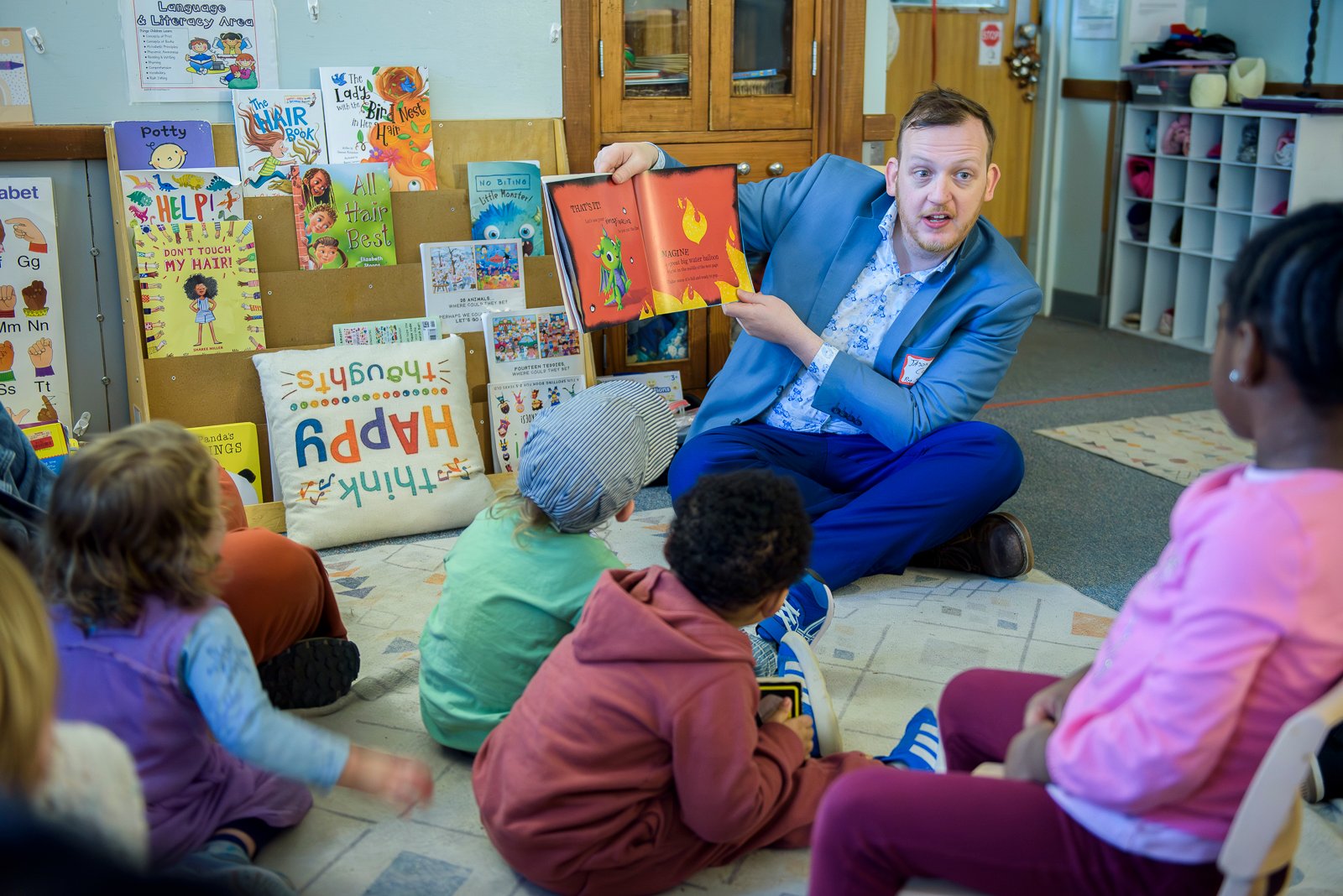 Man reads a book to children in a classroom.