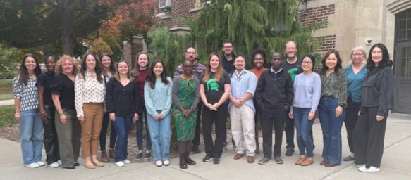 Men and women standing outside a brick building.