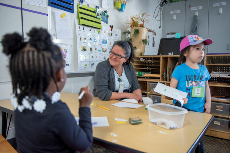 A teacher works on an activity with two chilren.