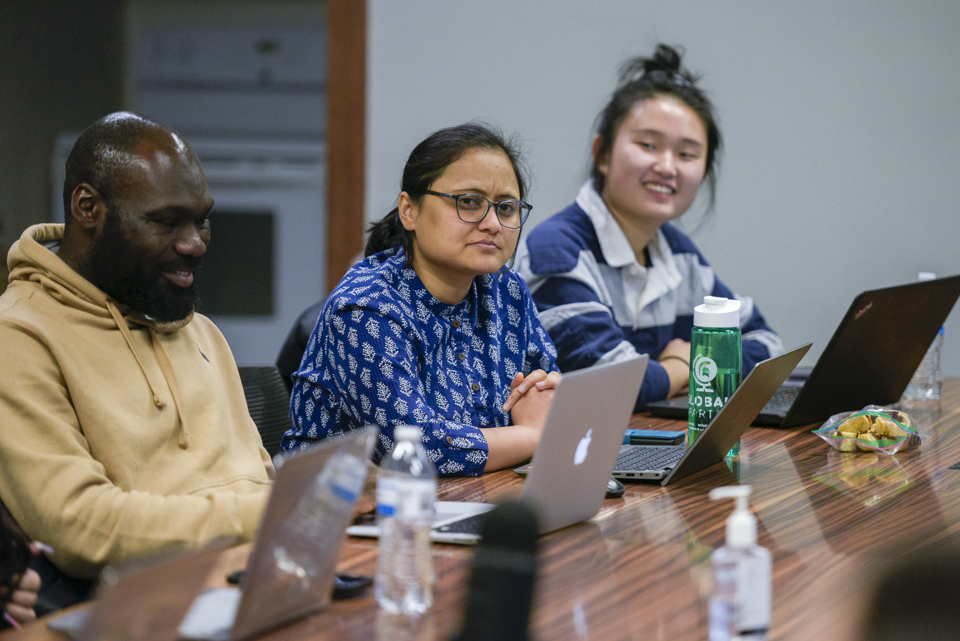Graduate students and faculty talking at a conference table.