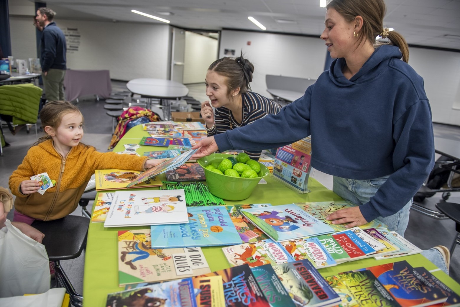 A young girl looks at children's books at a booth. 