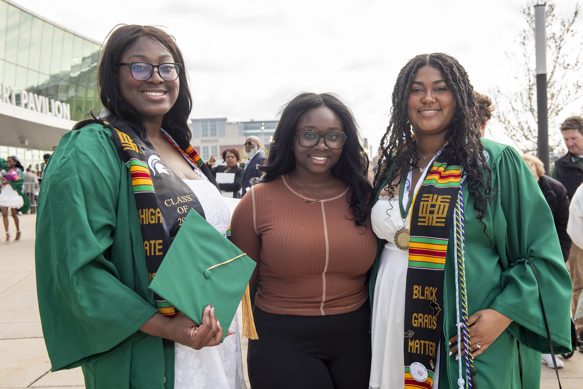 Three women stand in their graduation gowns.