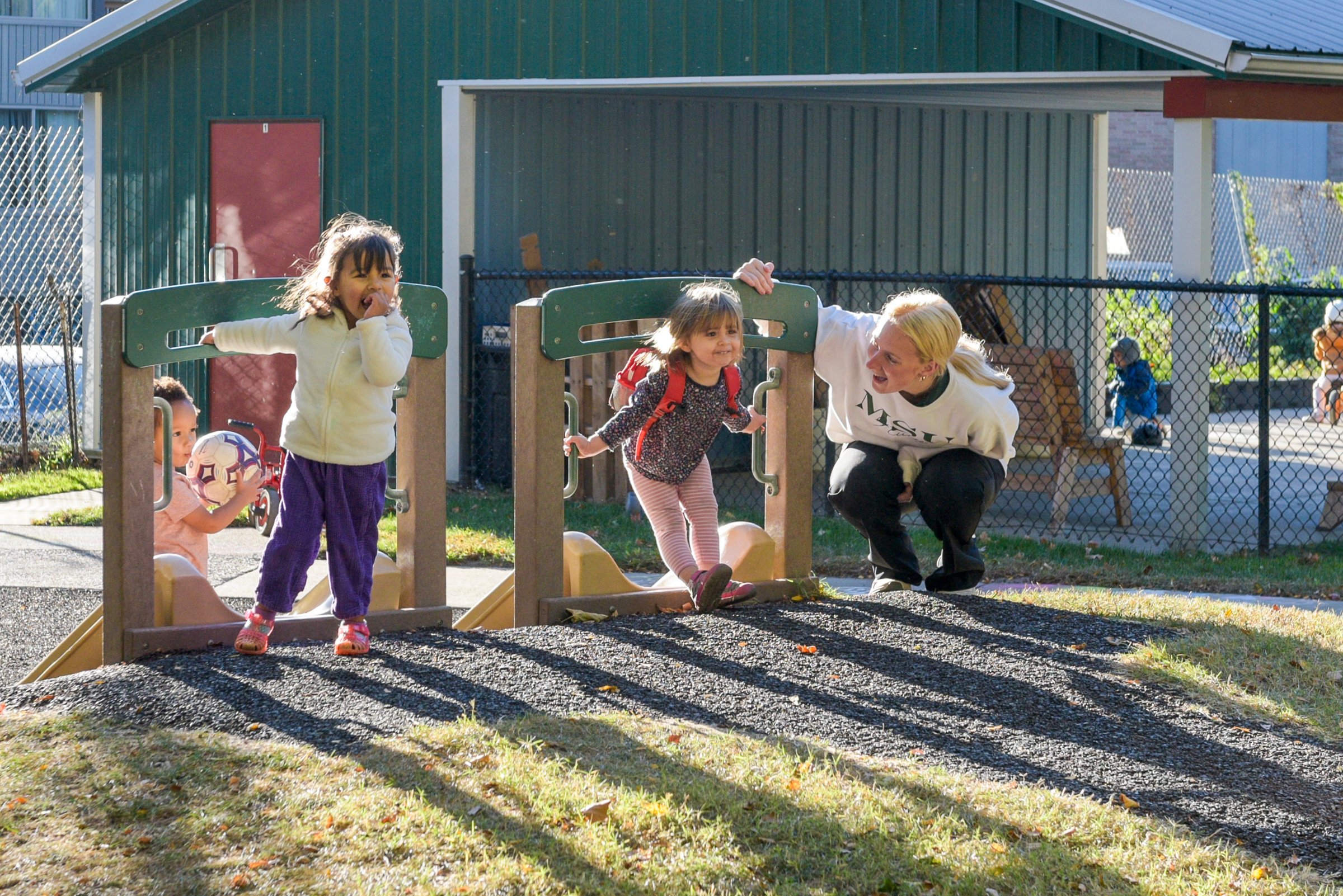 MSU undergrad plays with children on a playground.