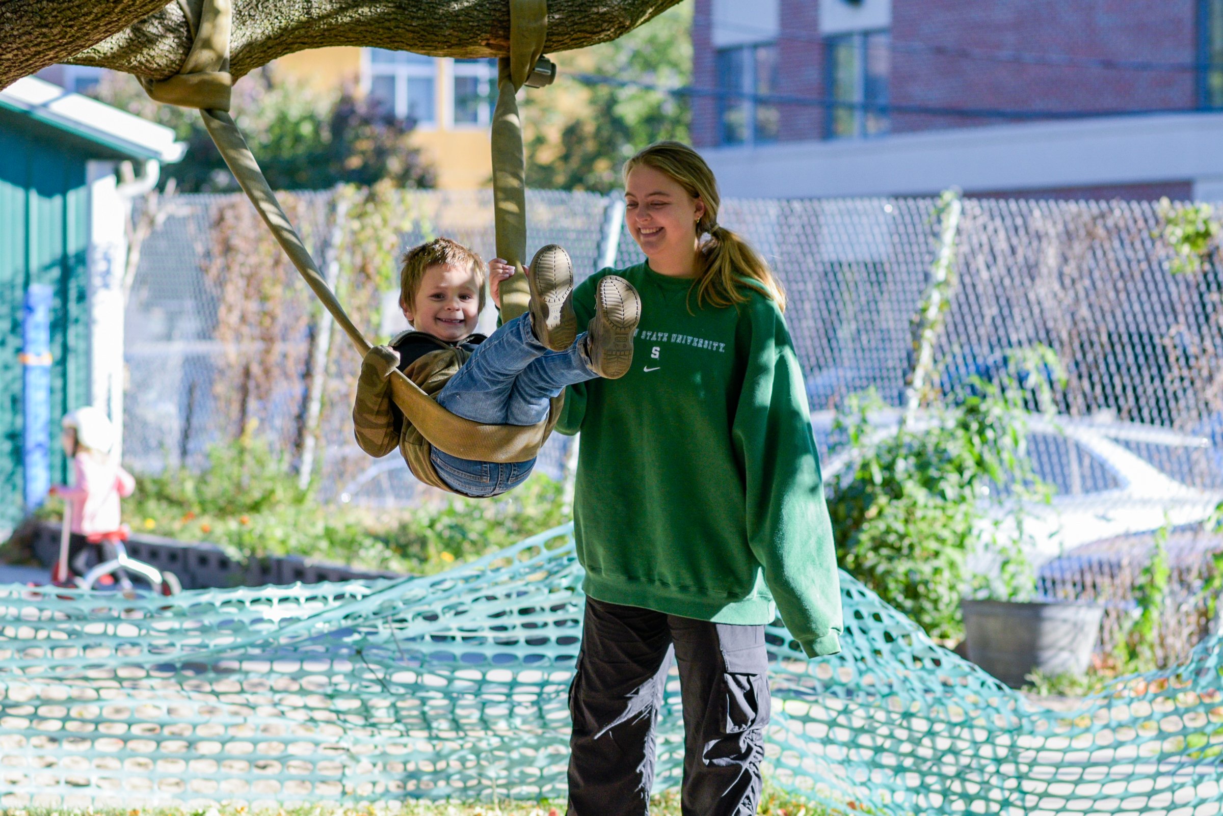 MSU undergrad pushes child on a swing.