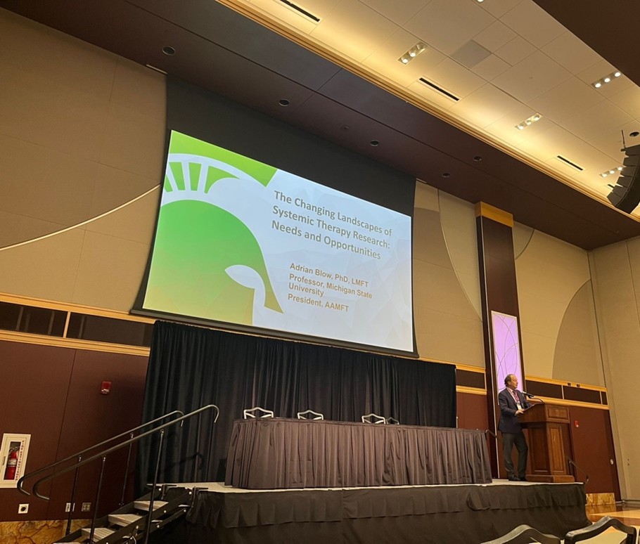 Dr. Adrian Blow presents at a podium. 