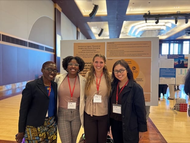 Four students smile with their arms around each other.