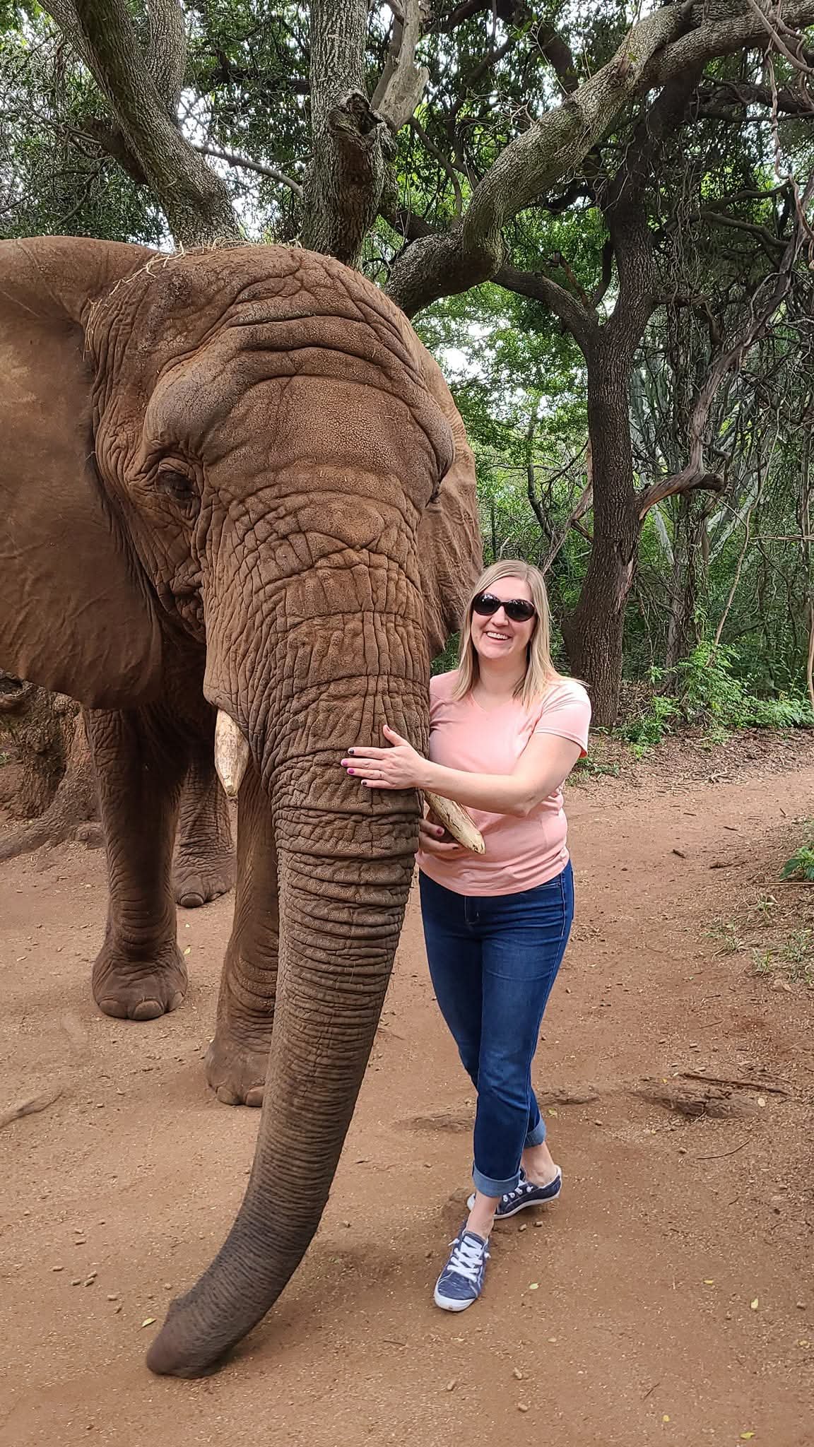 Sarah Douglas smiles next to an elephant.