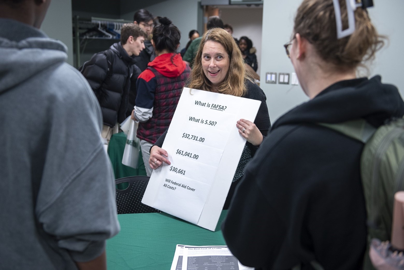 Woman presents a financial information poster to students.