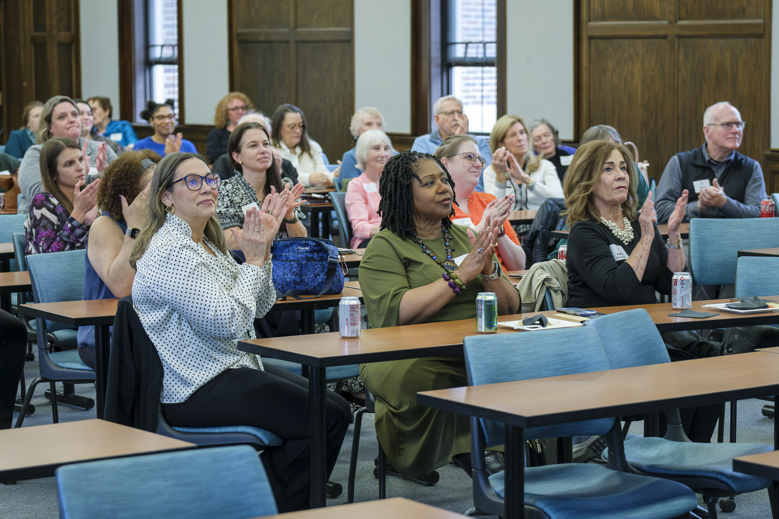People clapping while sitting in a large classroom.