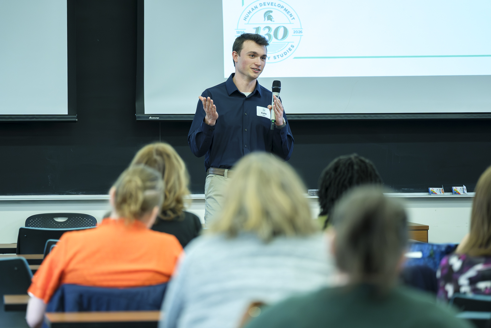 Man speaks to a group of poeole through a microphone.