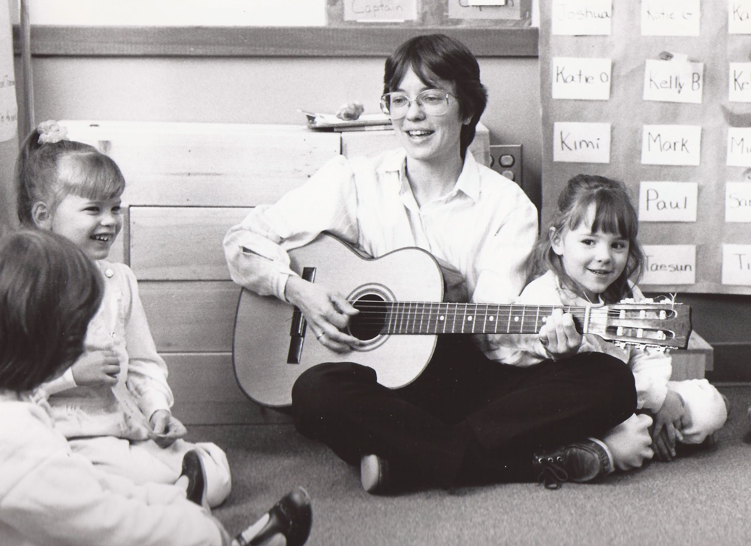 Woman with guitar sings to children.
