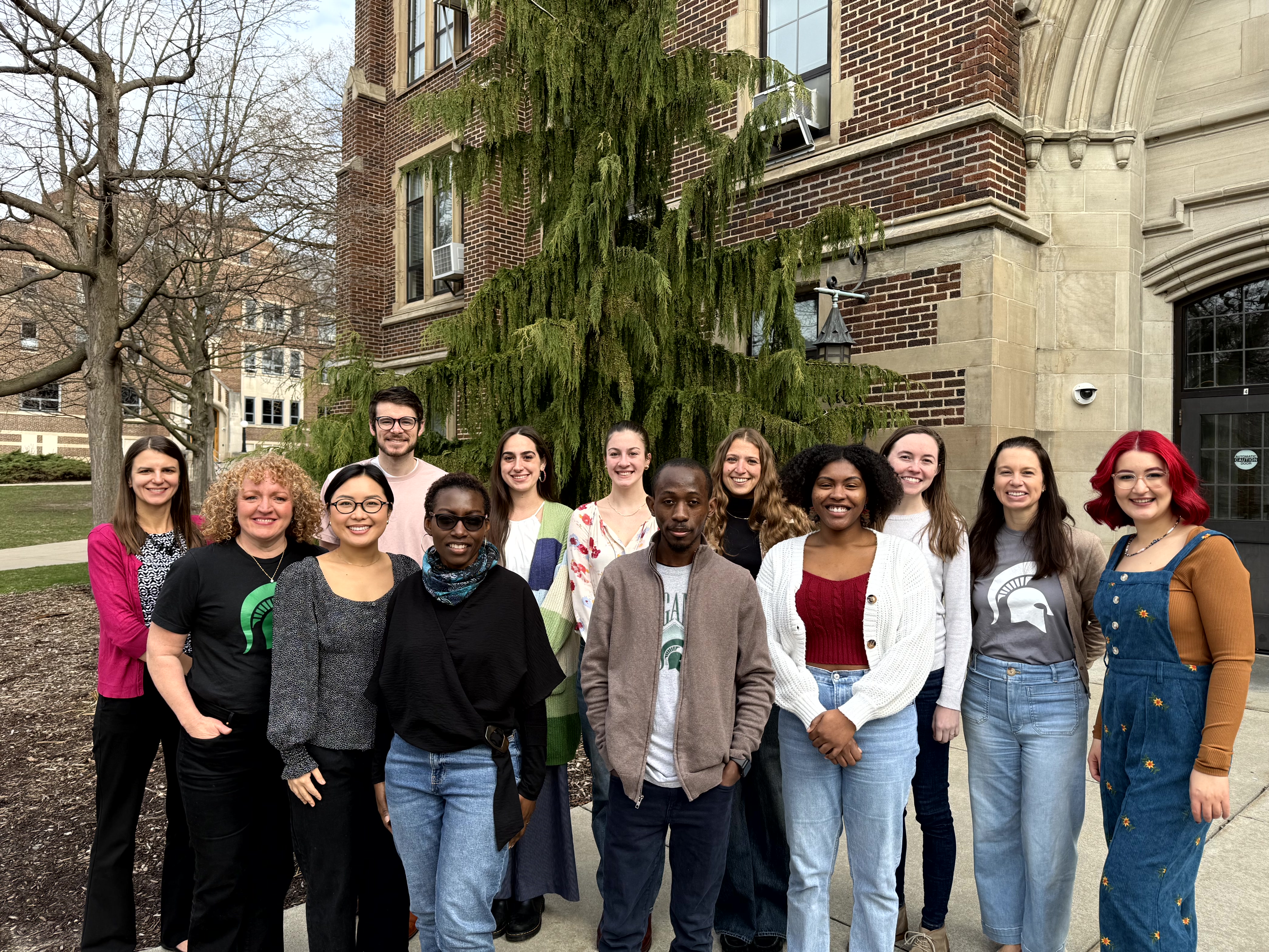 Faculty and student therapists smile as a group outside of the Human Ecology Building.