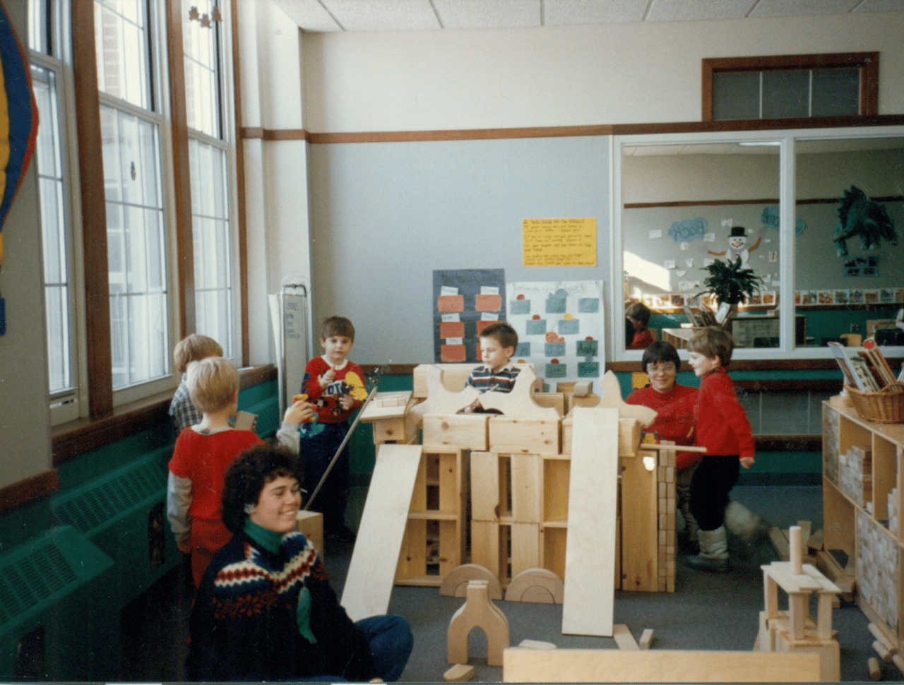 Teachers and students playing with wooden toys in a classroom.