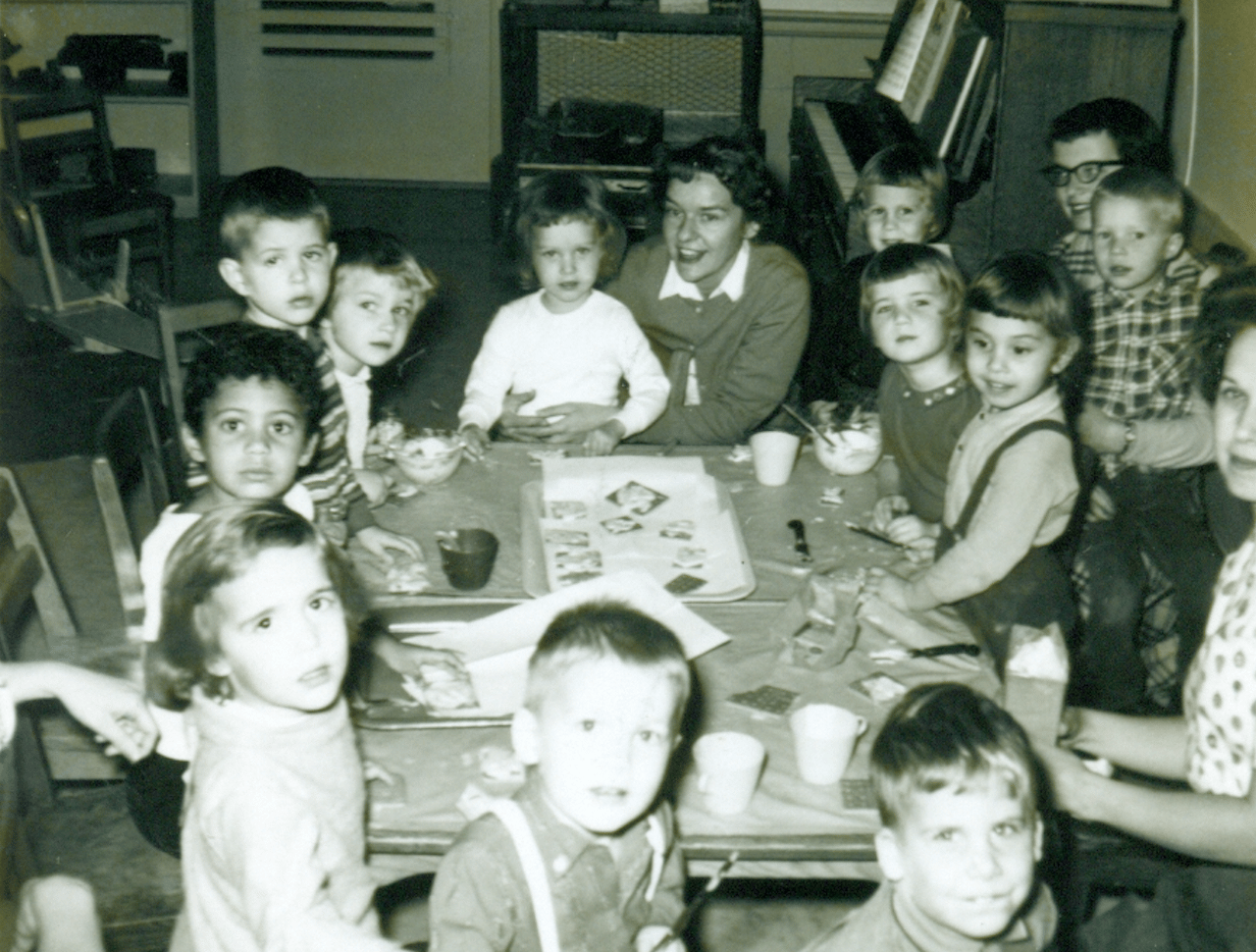 Children sitting at a table doing a project with teachers.