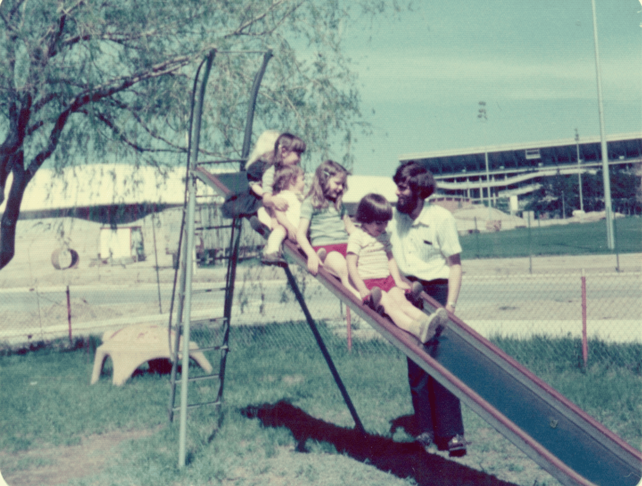 A teacher helps kids down the slide.