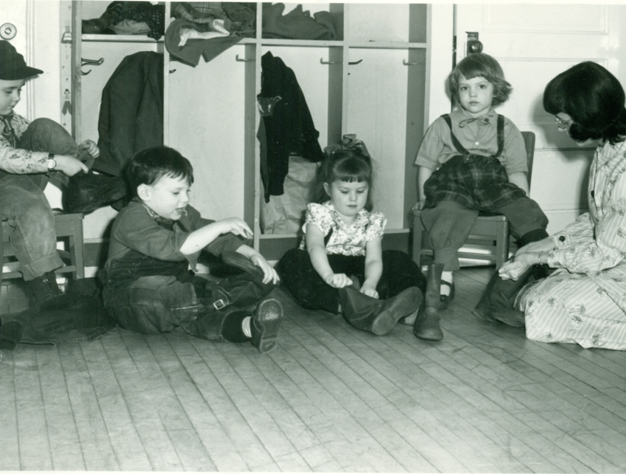 Children putting their shoes on in front of their cubbies.