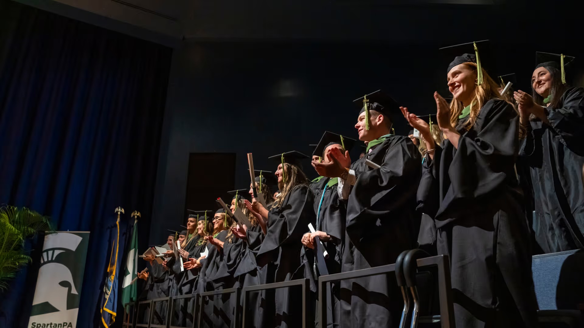 Graduating students clap during commencement ceremony.