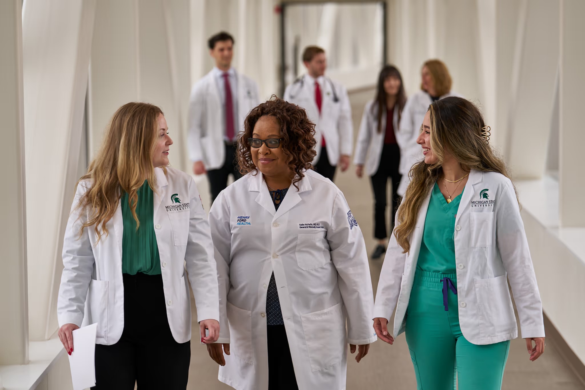 Medical professionals smile and converse while walking in medical building.