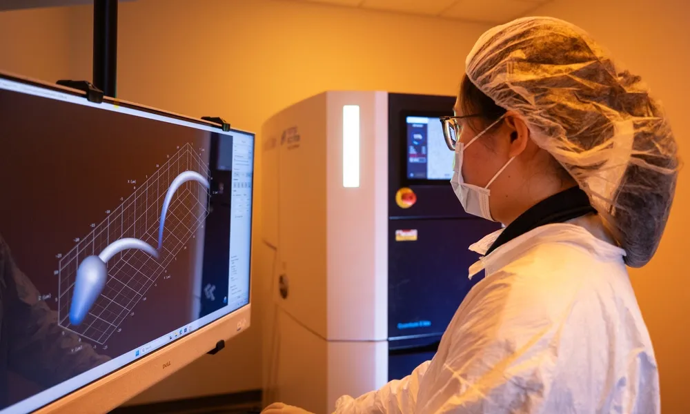 Reseacher in a gown looking at the design of the microbots.