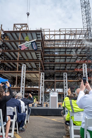 Crowd watching the beam be lifted into place on the building.
