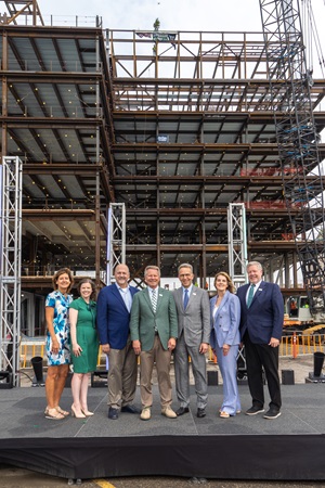 Leadership taking a photo of the beam in place on the research center.