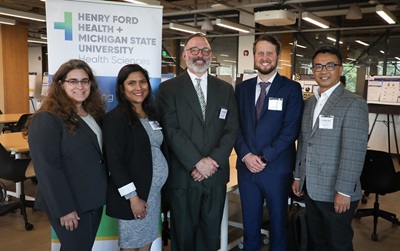 Event planning commmittee leaders posing in front of a banner and smiling.
