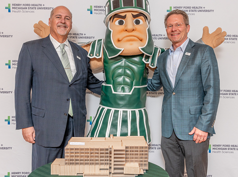 Henry Ford CEO and MSU President posing with MSU mascot Sparty