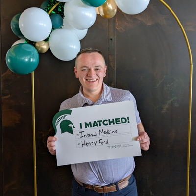 Dennis holding his match sign near ballons