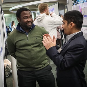 Two male cancer researchers discussing a poster