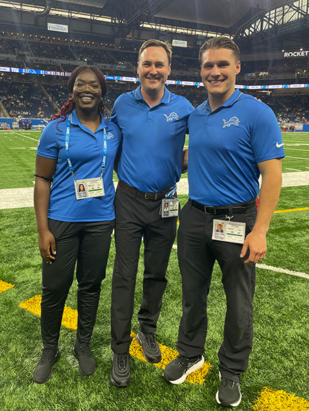 Ogeh standing with Detroit Lions Team Physicians on the football field.