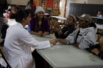 MSU medical student talking to high school students at a table.