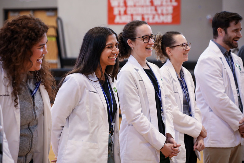 MSU CHM medical studnets laughing during the panel discussion and wearing white coats.