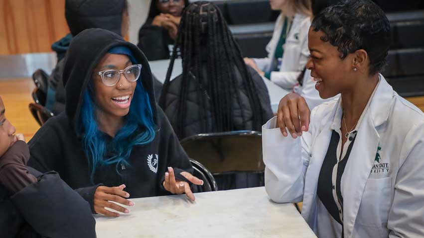 MSU medical student laughing and speaking with a Detroit high school student.