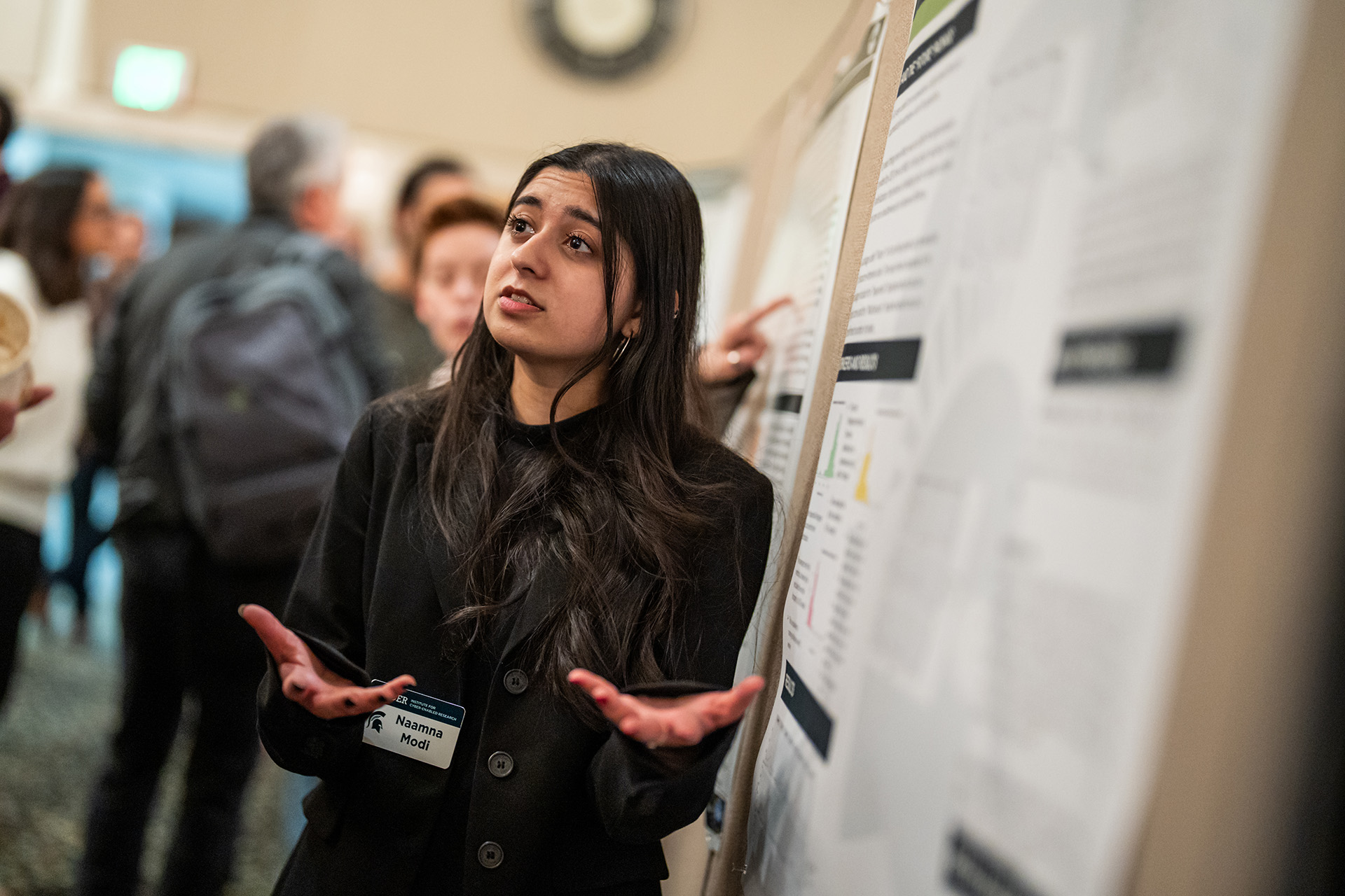 A student presents in front of an academic poster. 