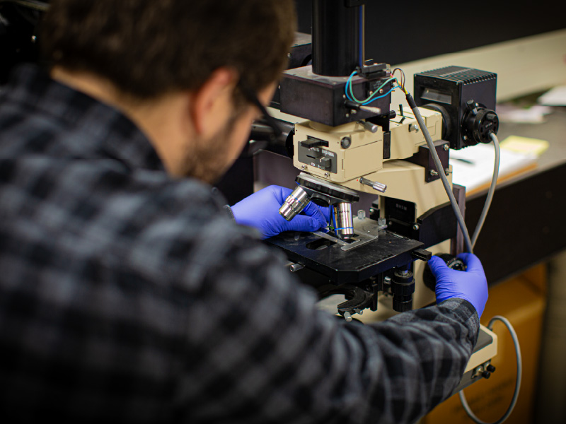 Ben Wenig making adjustments to a microscope that he is working with.