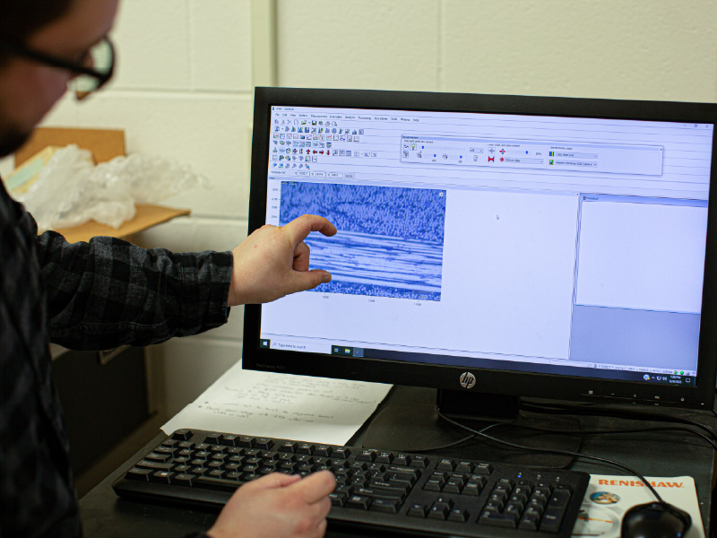 Ben Wenig standing in front of a computer screen pointing to a simulation he created.