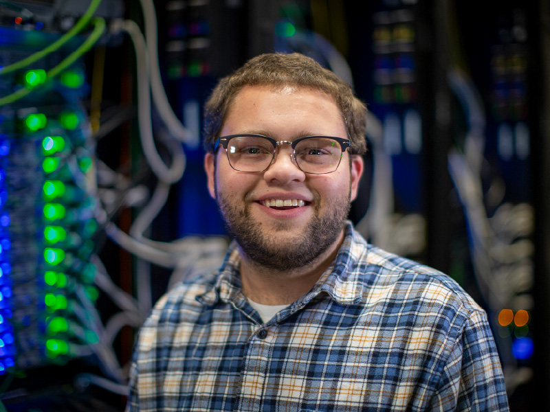 Ben Wenig standing in front of blue, green, and orange lights and white wires.