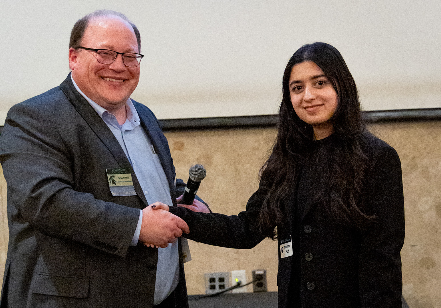 Naamna Modi shaking Brian O'Shea's hand at the 20th anniversary event.