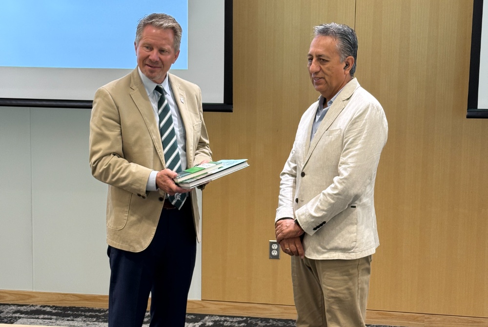 César Vallejo University Vice-Rector for Research Jorge Adrian Salaz Ruiz giving books to Michigan State University president Kevin Guskiewicz 