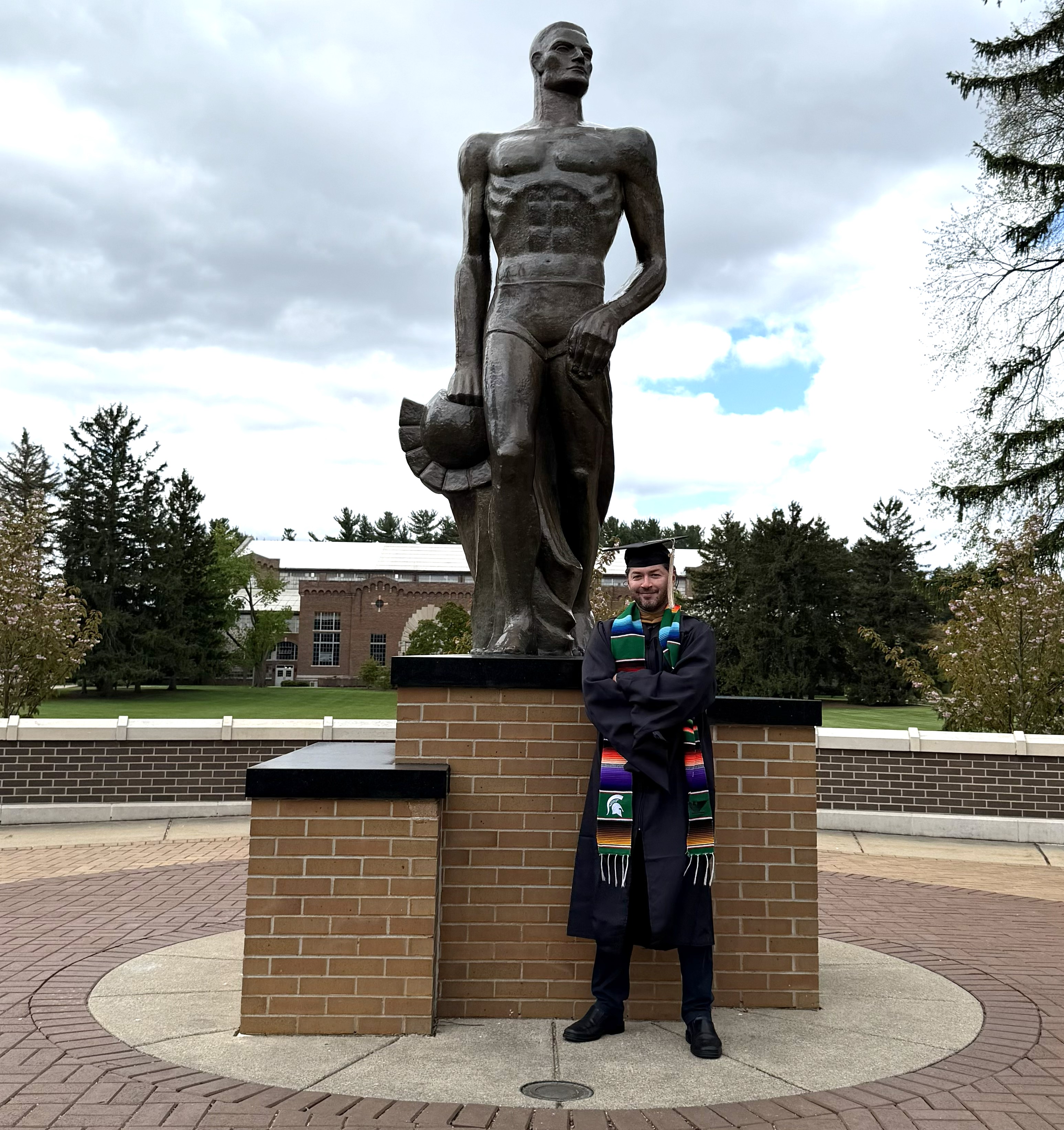 Adrian Oliveras standing next to the Sparty statue.