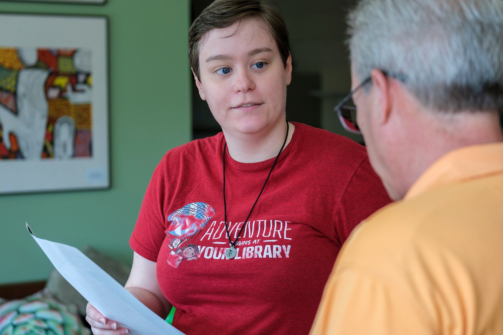 Two people engage in conversation during last year's open house. One person holds a sheet of paper and faces the other, Senior Advisor Regan Kania.