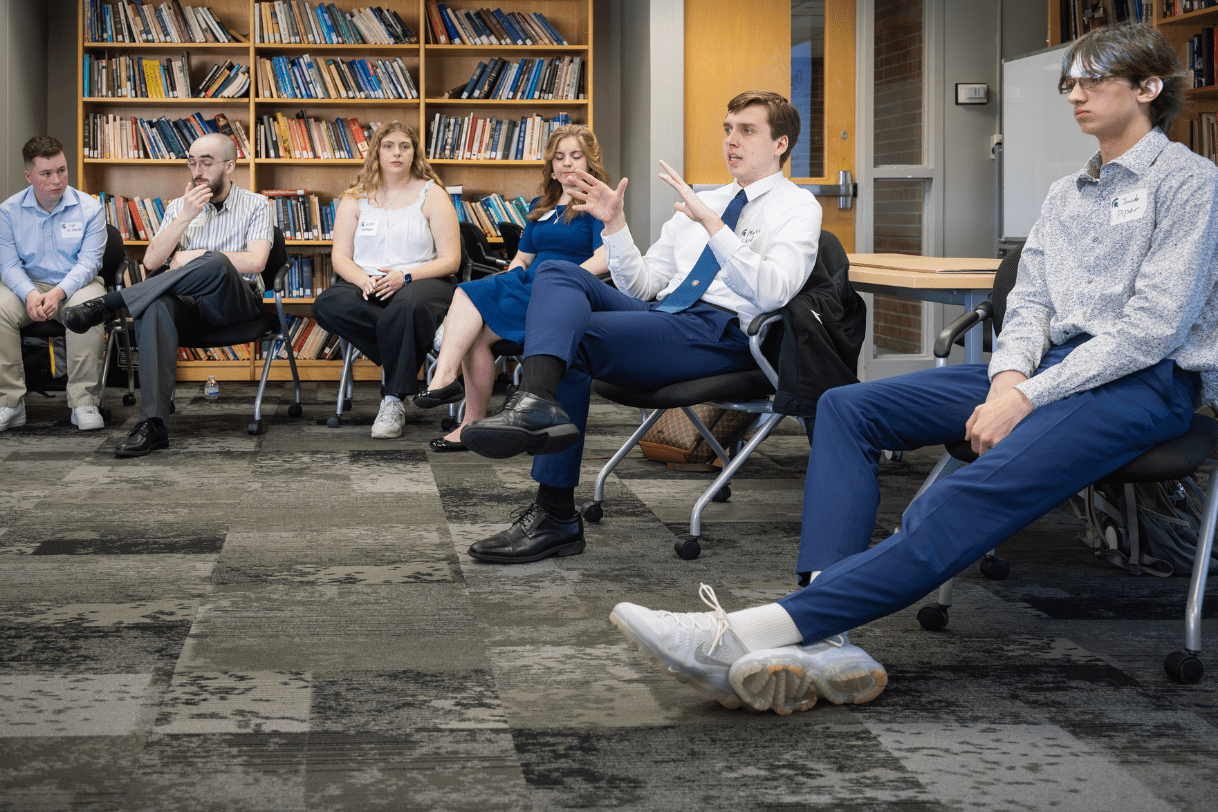 A group of six Madison students sitting in chairs in a semi-circle in discussion during the annual Research Showcase.
