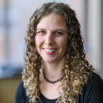 Emelia Hammond, smiling and wearing a black shirt with a necklace.