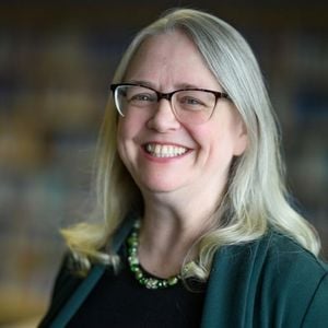 Vicki Essenmacher, smiling, wearing glasses and a green sweater