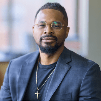 Jahshua Smith, JMC outreach and recruitment coordinator, wearing a blue blazer and glasses.