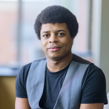 Orland Hawkins, wearing a black shirt and slivery grey vest.