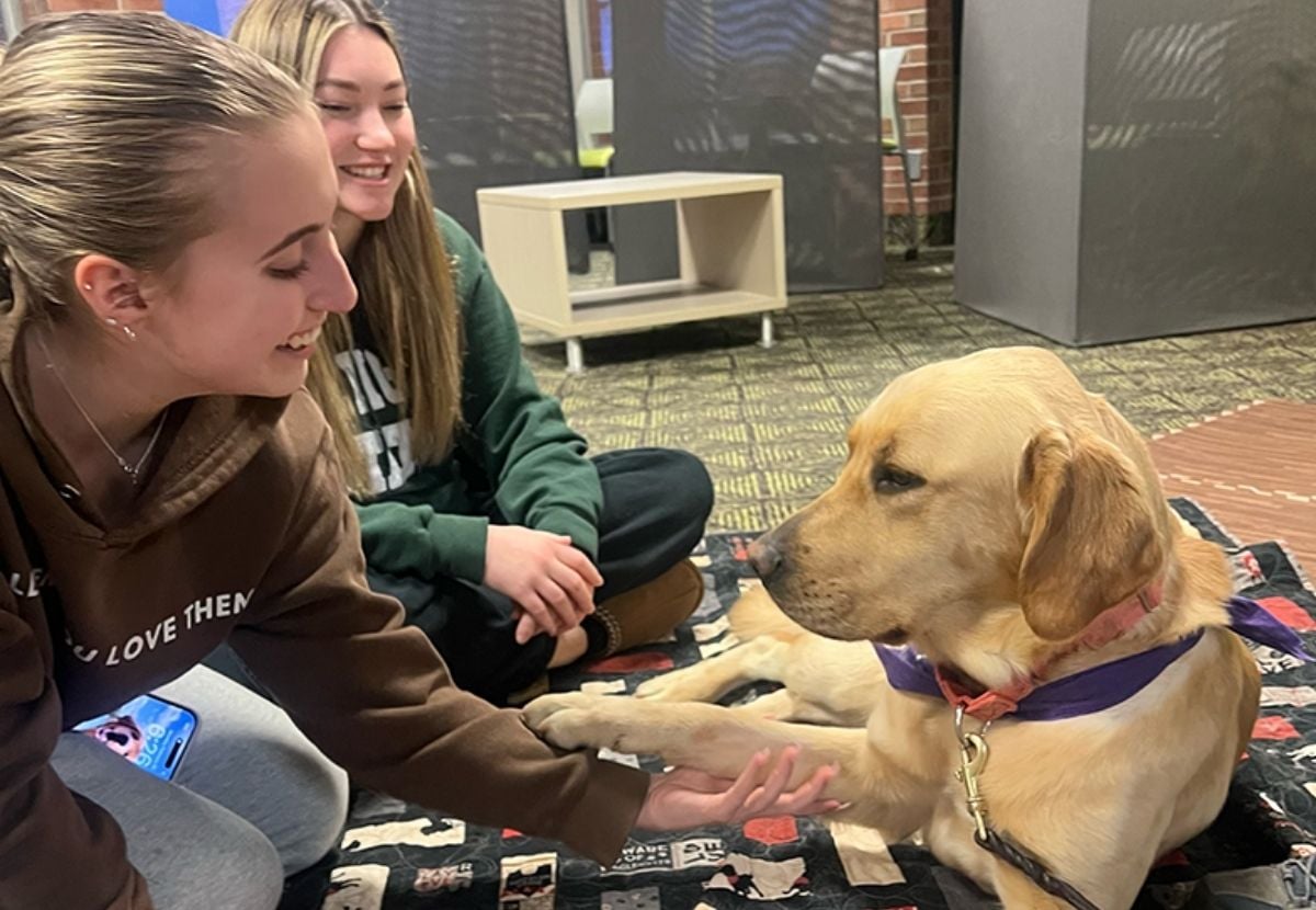 Photo shows two JMC students sitting with a therapy dog in Case Hall.