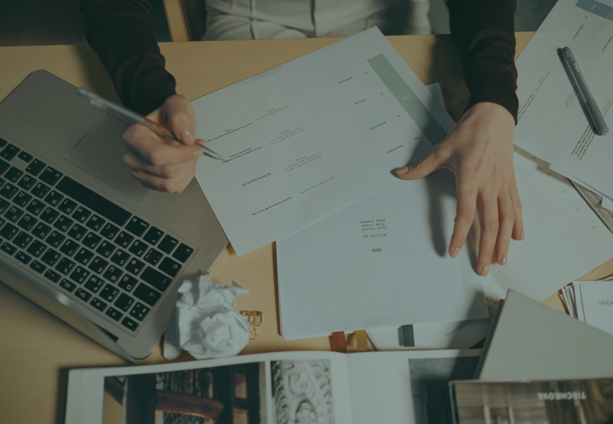 Overhead image of a person working at a desk with papers and a laptop in front of them.