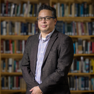 JMC Prof. Robert Brathwaite, photographed in the JMC Library wearing a blazer and collared shirt.