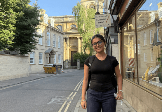 JMC student Jasnoor Kaur pictured smiling outside in Oxford, UK, in front of storefront windows.
